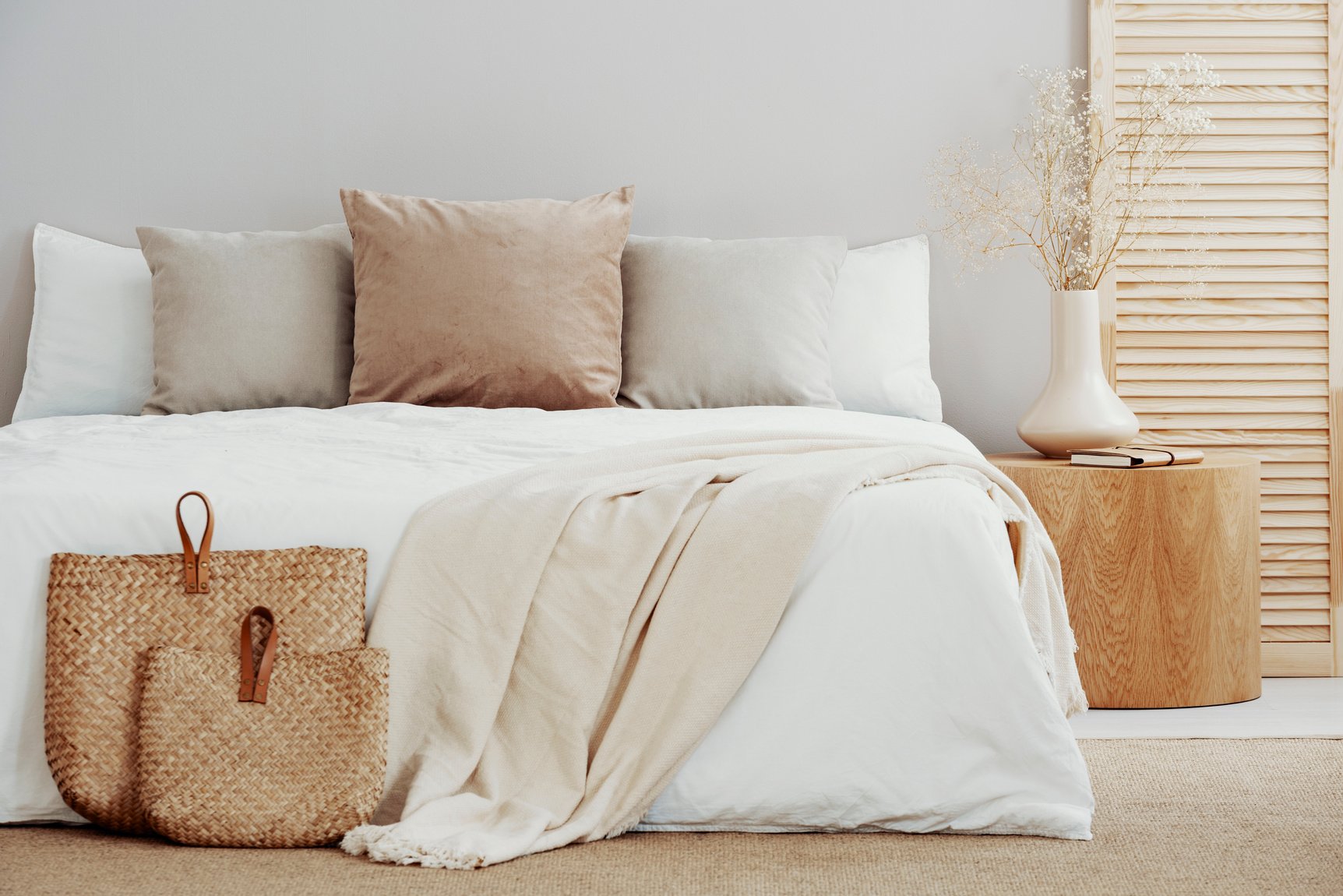 White and beige bedding on double bed in simple interior